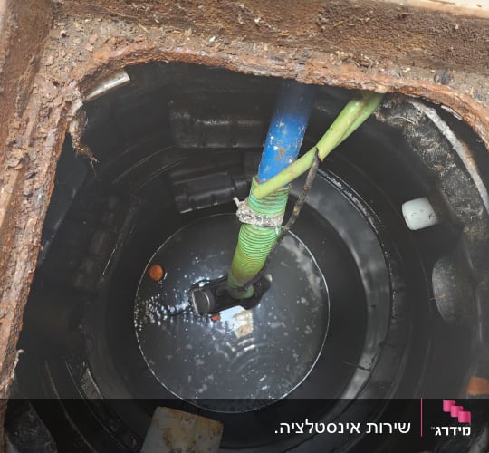 צינור ירוק וכחול בתוך בור ביוב עם מים